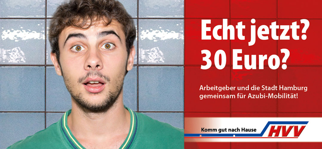 Auf dem Bild ist eine männliche Person mit einem überrascht aussehenden Gesicht vor einer Wand mit blauen Fliesen und einem Werbeplakat zu sehen. Das Plakat enthält Text auf Deutsch. Eine Person in einem grünen T-Shirt steht vor einer Wand mit blauen Fliesen. Ein rotes Werbeplakat mit weißem und schwarzem Text ist neben der Person sichtbar. Der Text auf dem Plakat lautet „Echt jetzt? 30 Euro? Arbeitgeber und die Stadt Hamburg gemeinsam für Azubi-Mobilität!“. Es gibt ein Logo am unteren Rand des Plakats, das „HHV“ und den Slogan „Komm gut nach Hause“ enthält.